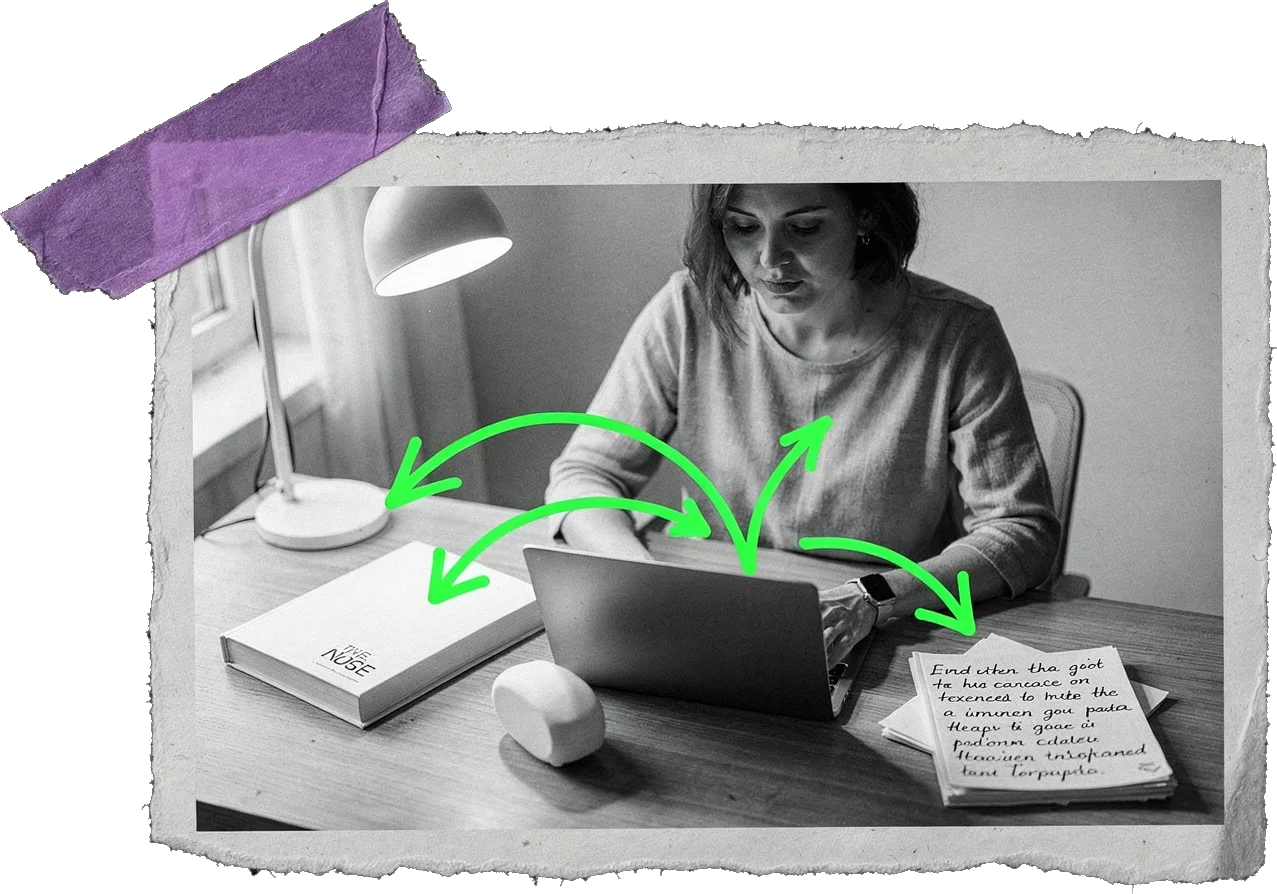 Black-and-white photo of a woman working at a laptop under a desk lamp, with green arrows pointing between the laptop, a book, a device and a handwritten page on the desk.