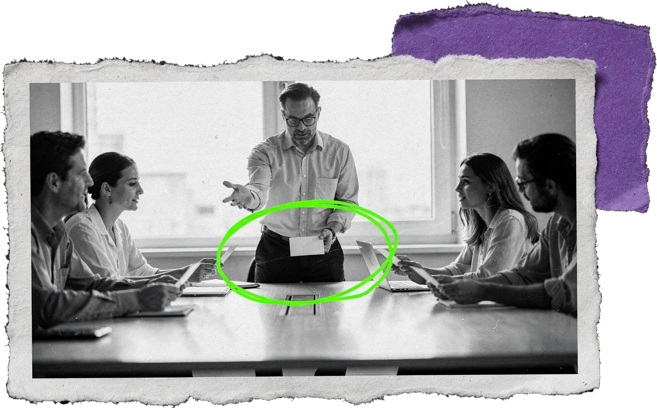 Black-and-white photo of a team meeting at a long table; a man standing at the head hands out a single sheet of paper, circled in green.