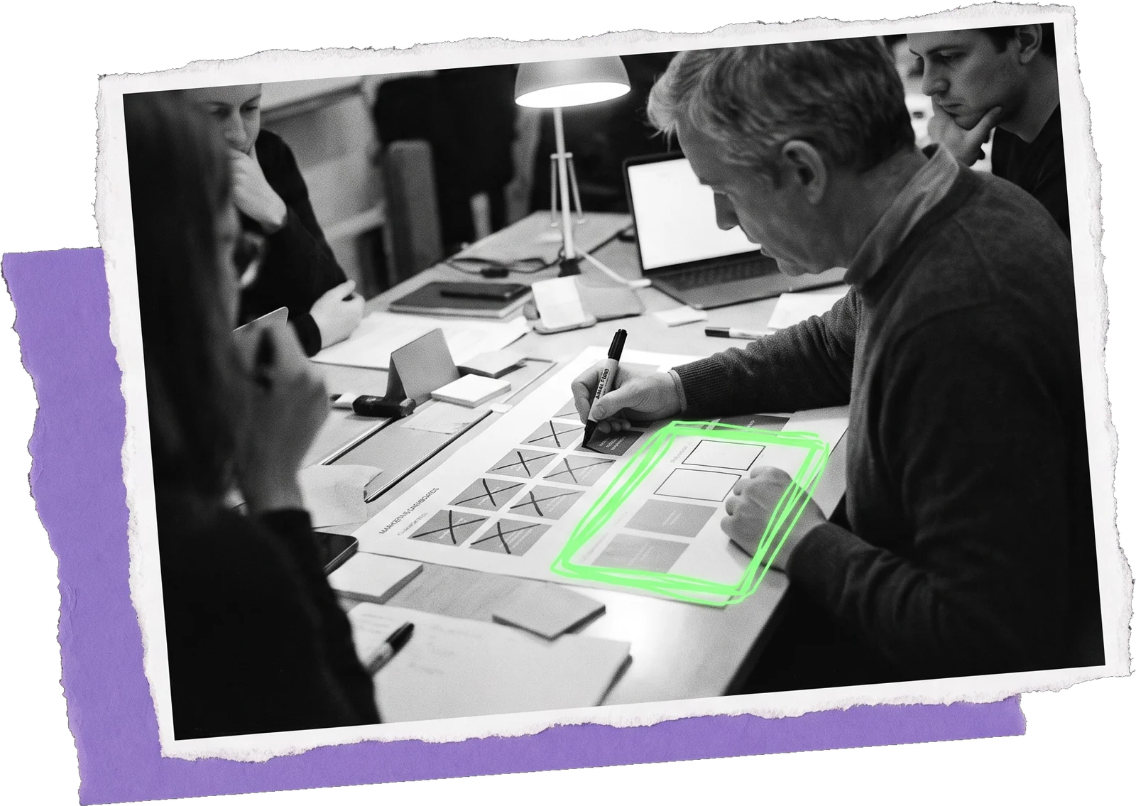 Black-and-white photo of a team around a table at night, one man sketching dashboard layouts on paper with several boxes crossed out and one highlighted in green; a line of text above reads "Marketing dashboards: from chaos to clarity".