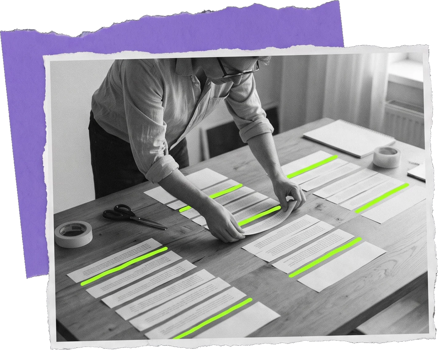 Black-and-white photo of a man arranging printed article drafts on a wooden table with tape and scissors; one green strip is marked on each page.