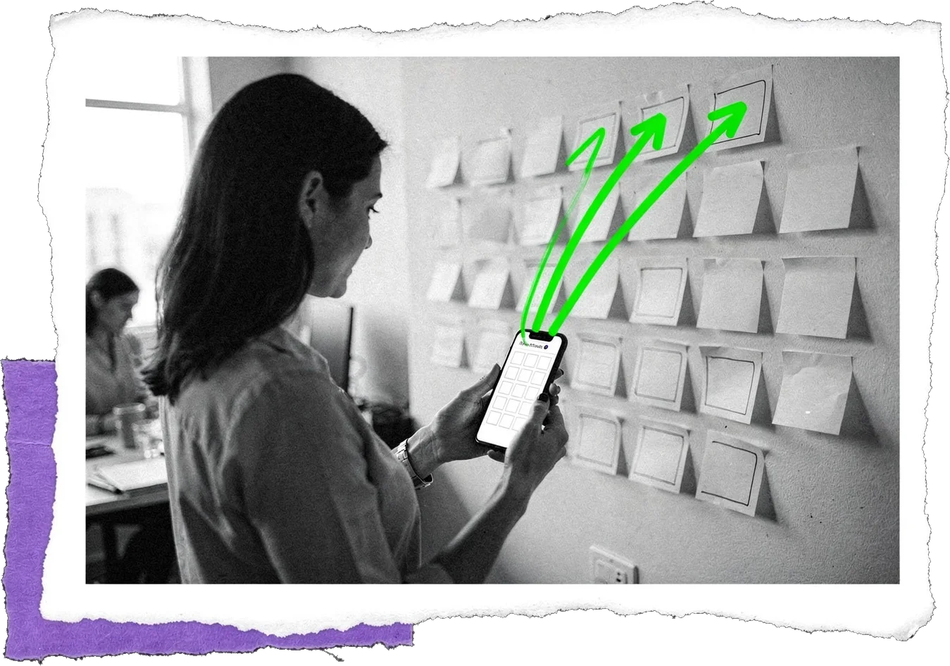 Black-and-white photo of a woman holding a phone in front of a wall of pinned cards, with green arrows rising from the phone toward the cards.