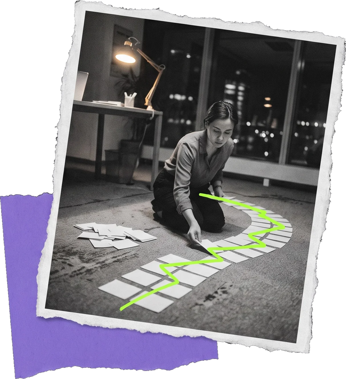 Black-and-white photo of a woman kneeling on an office floor at night, laying out a path of paper cards along a green line.