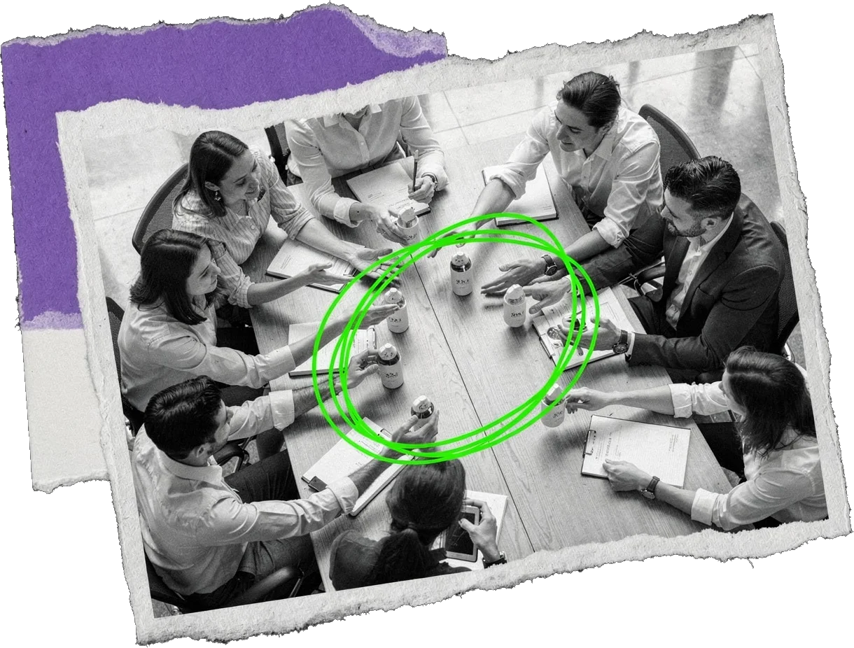 Black-and-white photo from above of a team around a table with coffee cups and papers, their hands reaching toward the centre; the middle is circled in green.